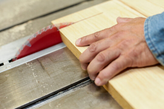 Hand guiding wood through table saw