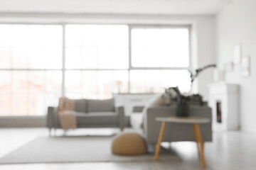 Obraz premium Blurred view of light living room with grey sofas and window