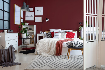 Obraz premium Interior of stylish bedroom with white folding screen, shelf unit and plants