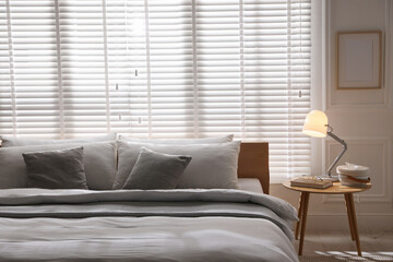Fototapeta premium Large bed with pillows and blanket near window in room