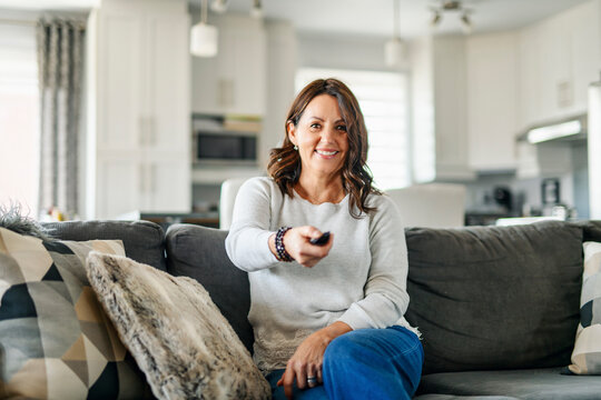 Beautiful aging. Portrait pretty mature female pensioner sit on sofa with remote control watching tv