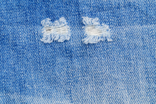 Rip and repair on denim fabric shows tear and stitching work done on blue jeans