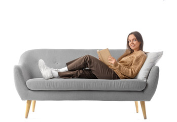 Fototapeta premium Young woman reading book on grey couch against white background