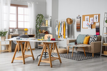 Fototapeta premium Interior of fashion designer's studio with workplace, sofa and clothes rack