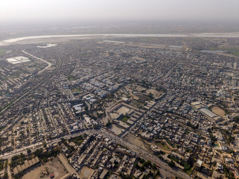 Aerial view of the dense urban sprawl and residential neighborhoods with the Indus River in the background in Hyderabad, Sindh, Pakistan.