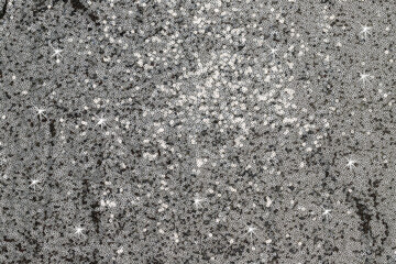 Naklejka premium Sparkling silver sequins cover a surface and reflect light during a festive event in the evening