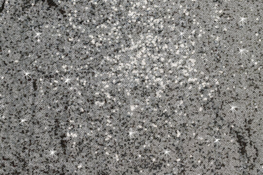 Sparkling silver sequins cover a surface and reflect light during a festive event in the evening