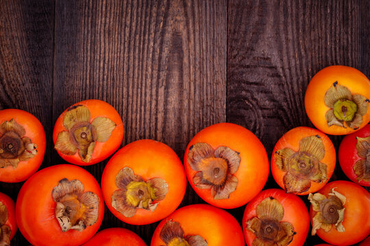 Persimmons arranged on wooden surface during daytime