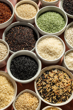 A variety of rice in white ceramic bowls on a tile surface 