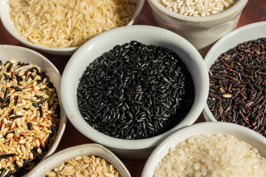 A variety of rice in white ceramic bowls on a tile surface 