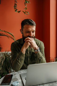 Bearded man working remotely on laptop in a cafe