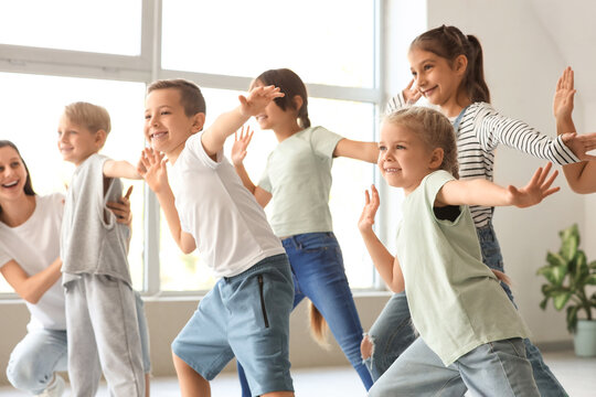 Group of little children with teacher dancing in studio