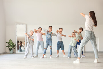 Naklejka premium Group of little children with teacher dancing in studio
