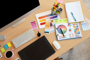 Naklejka premium Interior designer's workplace with graphic tablet and color palettes in office, top view