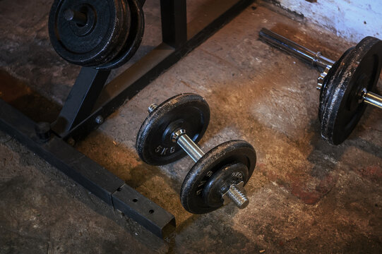 Home basement gym setup with dumbbells barbell weights on concrete floor