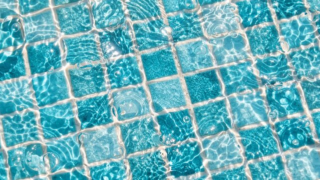Crystal clear turquoise pool water with square mosaic tiles, 16:9.