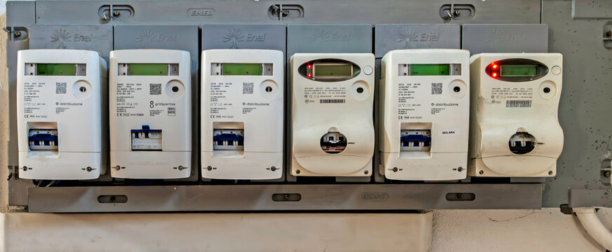 A row of Enel e-distribuzione digital electricity meters and circuit breakers installed in a building in Olbia, Sardinia, Italy.