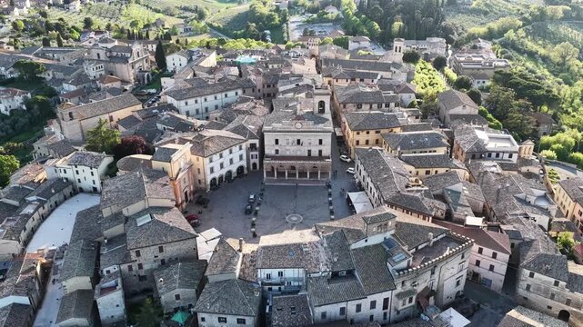 Aerial view of the circular Piazza del Comune surrounded by historic stone buildings and rooftops in Montefalco, Umbria, Italy.