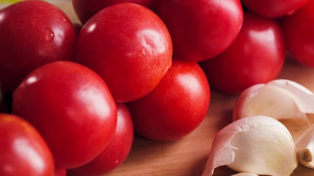 Close up of fresh red tomatoes and garlic on wooden surface, healthy ingredients for cooking concept. High quality 4k footage