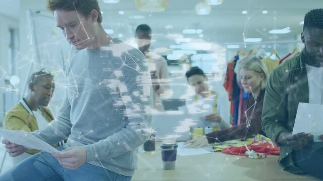 Man in sweater flipping sheets as team sorting swatches, overlay appearing linking work for design