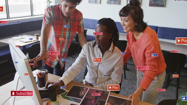 Seated photographer adjusting edits on monitor after colleagues pointing at prints to finalize shot
