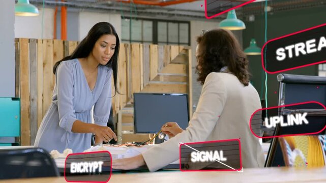 Two women leaning and pointing at model, planning network as ENCRYPT SIGNAL floating over model