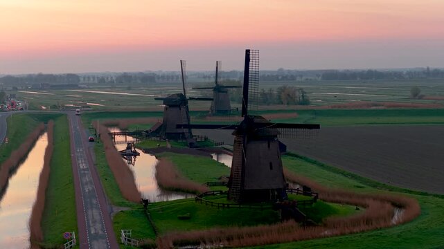 Aerial view of historic windmills standing along canals in the polder landscape at sunset Schermerhorn, North Holland, Netherlands.
