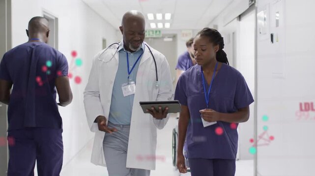Doctor tapping tablet activating LDL graphics while walking clinic hall, nurse reviewing data