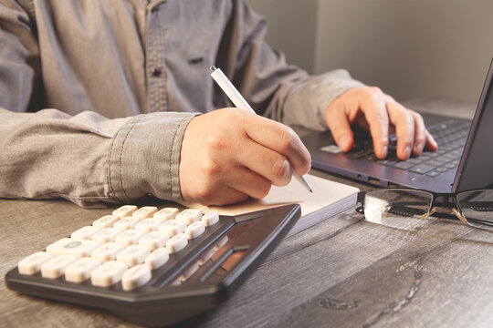 Man working with calculator and laptop on wooden table. Business concept.