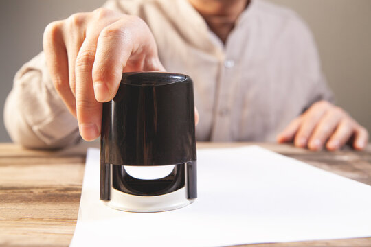 Man holding a black ink bottle on a sheet of white paper.