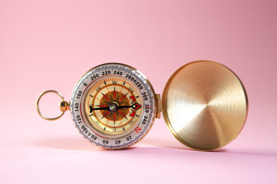 Compass on a pink background. Conceptual image of travel.