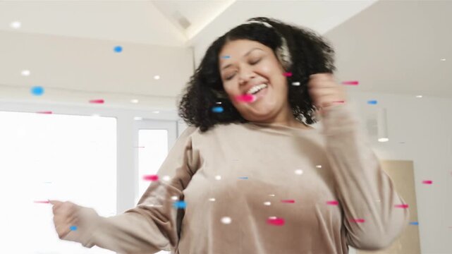 Confetti appearing, woman raising arms, laughing, standing, donning headphones, dancing to beat