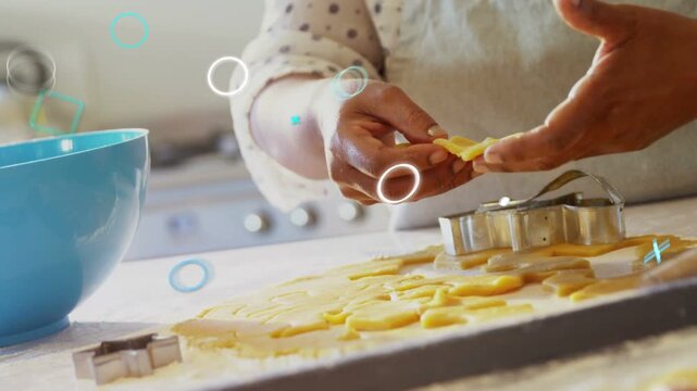 Baker hands pressing cutter into dough on counter, filling tray as graphics drifting over hands