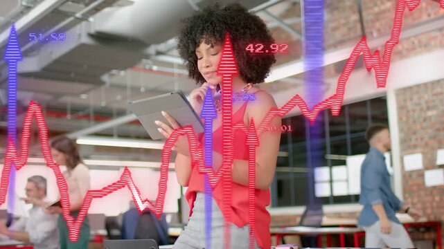 Woman at desk tapping tablet causing red jagged charts and blue arrows tracking market data