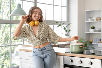 Cool young woman dancing and cooking in kitchen
