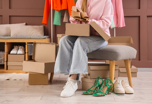 Woman putting stylish shoes into box at home