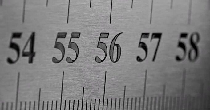 Slow Pan Over Metal Ruler. Smooth slow movement across extreme close-up of metallic ruler with black numbers and brushed surface.