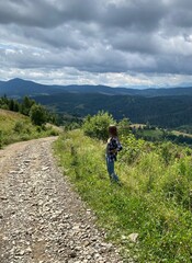 Fototapeta premium Woman Standing on Mountain Road, Looking at Scenic Landscape, Travel and Freedom Concept