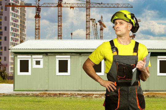 Modular construction, Mobile office buildings. Site supervisor inspects prefabricated office unit at construction site with cranes, temporary workspace installation.