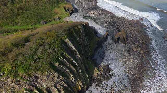 Aerial view of Mouthmill Beach which is a secluded pebble cove near Clovelly, North Devon, known for the dramatic Blackchurch Rock sea arch and waterfall. Ambient exploration by drone. 
