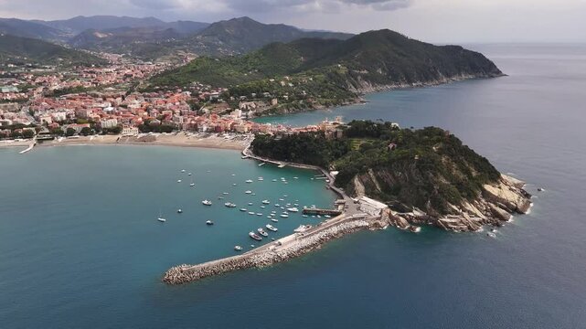 Aerial view of the Sestri Levante peninsula featuring the harbor, colorful buildings, and lush green hills overlooking the Mediterranean Sea, Sestri Levante, Liguria, Italy.