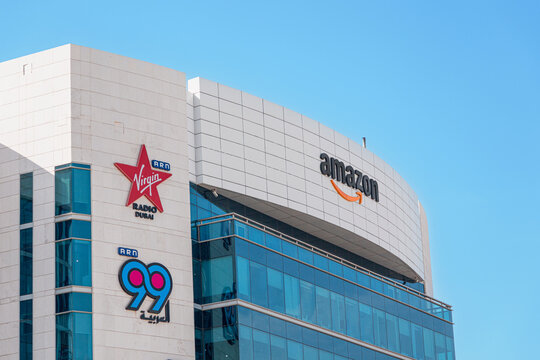 14 January 2026, Dubai, UAE: Logos of well known international companies Amazon, Virgin Radio Dubai, and ARN 99 on a modern office building facade