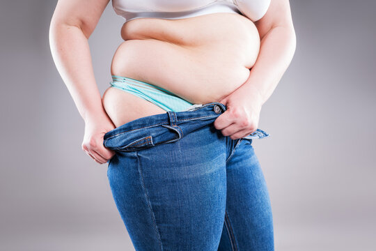 Plus size woman pulling up tight jeans. Overweight, weight loss and body positive concept