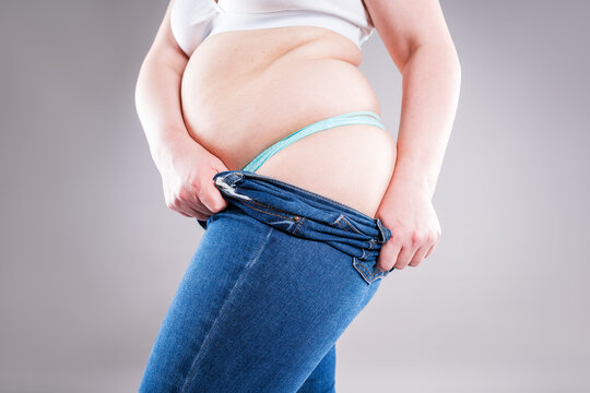 Plus size woman pulling up tight jeans. Overweight, weight loss and body positive concept