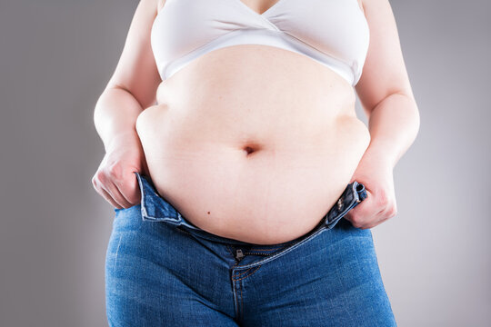 Plus size woman pulling up tight jeans. Overweight, weight loss and body positive concept