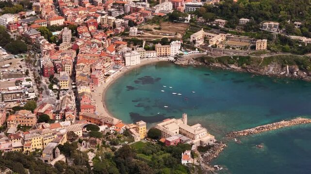 Aerial view of the Baia del Silenzio with its turquoise waters and colorful historic buildings along the coastline in Sestri Levante, Liguria, Italy.