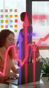 Vertical video: Analyst typing as peer pointing at notes, waves sweeping, showing business data