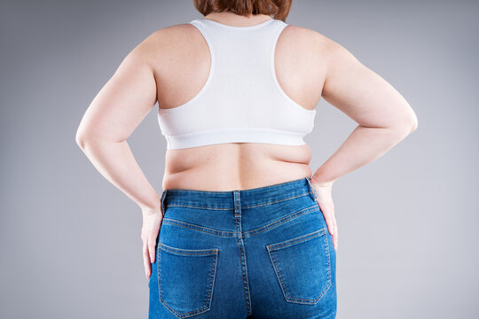 Overweight woman in tight jeans showing love handles and back fat folds, weight loss concept