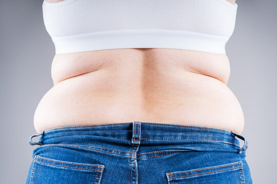 Overweight woman in tight jeans showing love handles and back fat folds, weight loss concept