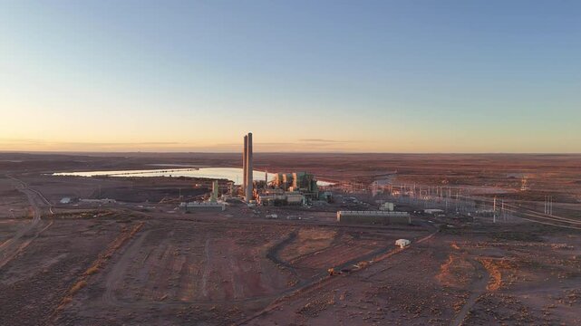 Aerial view of Cholla Power Plant with its tall smokestacks and cooling ponds in the desert landscape at sunset in Joseph City, Arizona, United States.